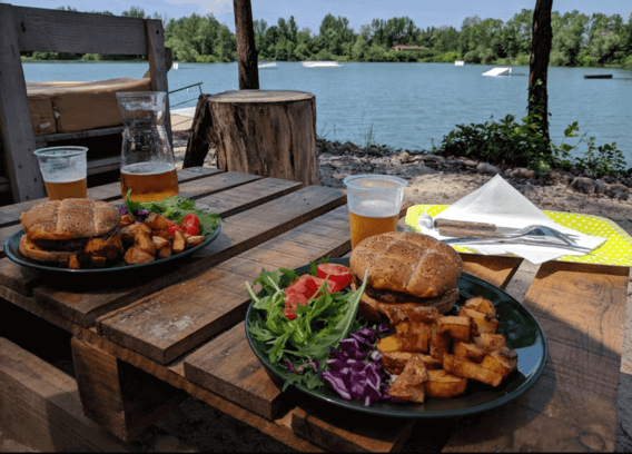 deux assietes de burger avec des patate et de la bierre vue sur le lac